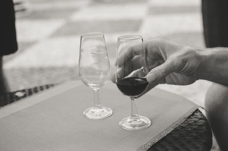 Closeup on human hand holding wine glass, bar restaurant terrace on backgroundの写真素材