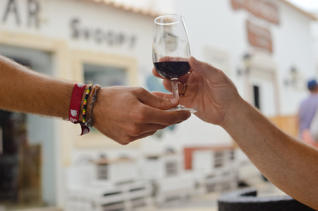 Closeup on person's hand serving holding a glass of wine for tasting.