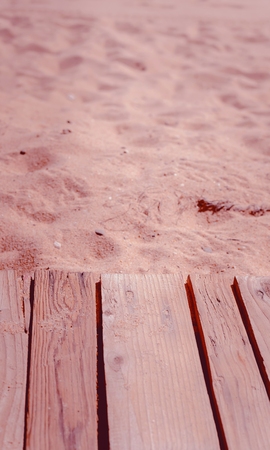 Top view of wooden beach boardwalk with sand texture backgroundの写真素材