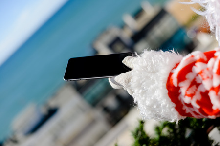Christmas Busy Joyful Santa Claus Using Mobile Smartphone on sunny outdoors background. Back side...