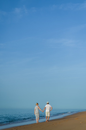 Romantic travel vacation. Joyful male and female couple lovers walking on sand beach sunny outdoors backgroundの写真素材