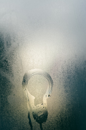 Abstract blurry background of foggy window with light bulb drawing, rainy season.の写真素材