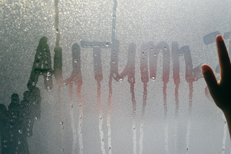 Hand on foggy rainy window, abstract background. Closeup view of emotional feelingsの写真素材