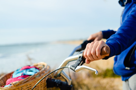 Person holding bicycle on natural beach outdoors background. Closeup imageの写真素材