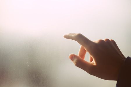 Hand draws on cold fogged window background, closeup imageの写真素材