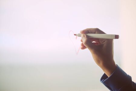 Hand draws on cold fogged window background, closeup imageの写真素材