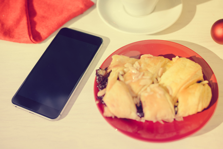 Mobile smartphone, coffee and pastry on light background. Closeup photo flat lay styleの写真素材