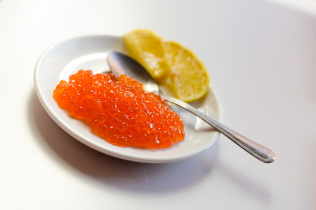 Red caviar with spoon and lemon on white background. Close up image of delicacy food luxury lifestyleの写真素材