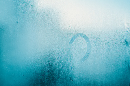 Question mark symbol on sunny foggy window glass blurry condensation background, closeup image. Research and development scientific innovationの写真素材