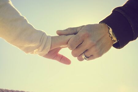 Female male couple touching hands on sunny outdoors background. Close up view of emotional feelings