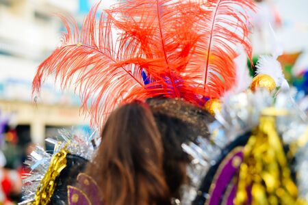 Close up on unrecognizable joyful dancing woman wearing carnival feathers costume on street outdoors background. Back view photographyの写真素材