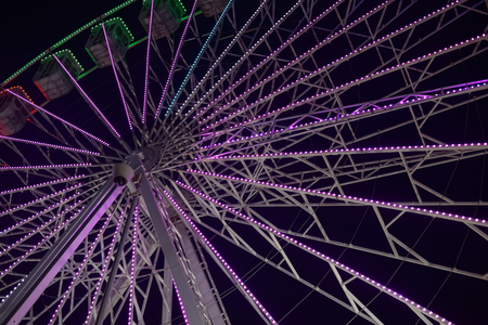 Colorful blurry lights of amusement park ferris wheel and rollercoaster on the night backgroundの写真素材
