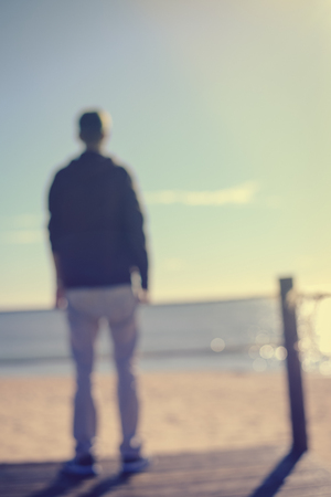 Back view of defocused unrecognizable man on the beautiful travel sea background. Sunny water horizon natural outdoorsの写真素材