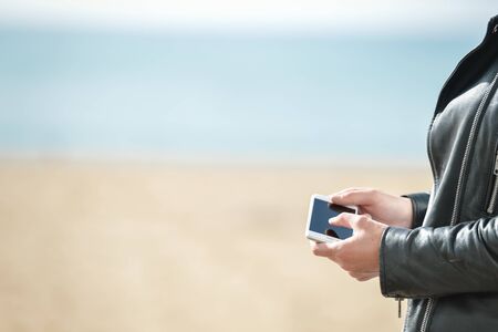 Closeup on hand using working on smartphone on outdoors background.の写真素材