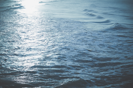 Blue waves of the sea and foam background with sun light reflectionsの写真素材