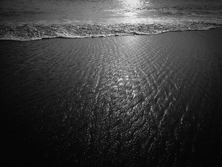 Black abstract natural sandy beach closeup, volcanic seacoast background. Space surface for textの写真素材