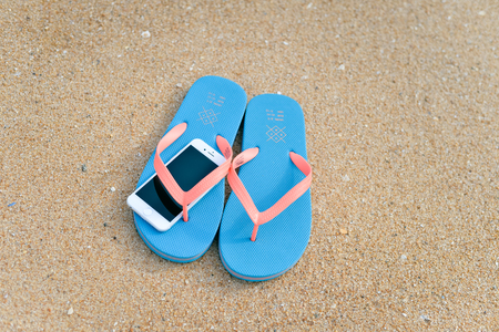 Algarve, Portugal - April 30, 2016: Top view on iPhone 6 mobile phone with slippers on sandy summer beach background, close up photoのeditorial素材