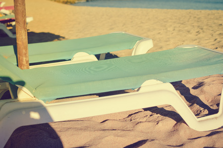 Holiday beach chaise lounges and parasol canopy on the ocean outdoors background.の写真素材