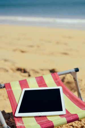 Albufeira, Portugal - 10 October, 2016: Apple Ipad 2 tablet computer on the beach outdoors background. Closeup shot vacation. mobility e-reader, smart pad on chairのeditorial素材