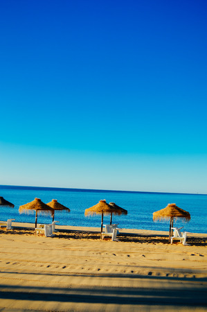 Beach umbrellas and couches on blue sky outdoors backgroundの写真素材