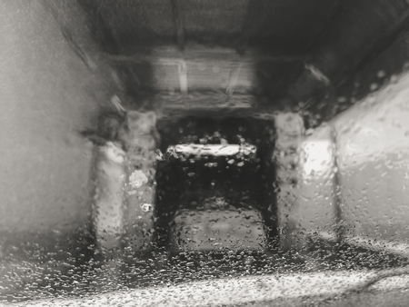 Blurred macro closeup on wet surface window at the car wash, condensated abstract background. Automated self cleaning, maintaince systemの写真素材