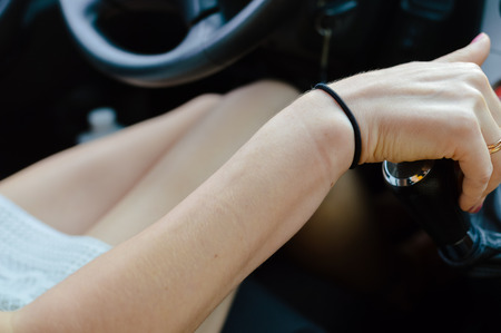 Blurred closeup image of driving person hand on car interior background
