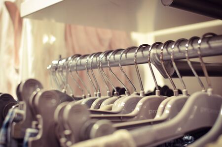 Closeup on shopping clothes hangers on rail in a designer store indoor background. Shallow depth of...