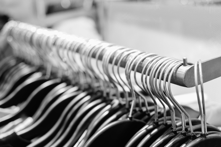 Closeup on shopping clothes hangers on rail in a designer store indoor background. Shallow depth of field of promotional marketing campaign department store design spaceの写真素材