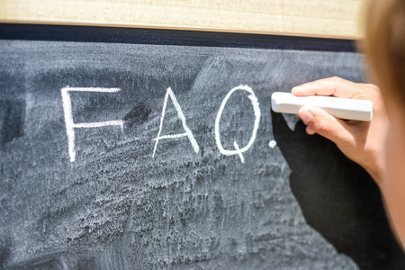 Child hand drawing FAQs - Frequently Asked Questions text on the blackboard. Education thoughts hot ideasの写真素材