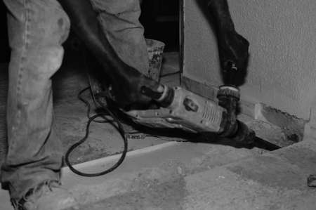 Closeup on construction worker doing renovation work holding tools on building backgroundの写真素材