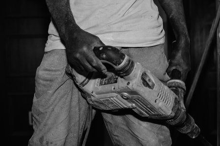 Closeup on construction worker doing renovation work holding tools on building background