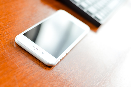 Lisbon, Portugal - March 23, 2017: Closeup on Apple iPhone 7 smartphone and computer pc keyboard on light table background. Mock up black display copy space, flat lay top side viewのeditorial素材