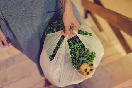 Close up on person holding bag from vegetables food market, abstract shopping background. Buyer...