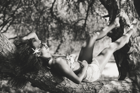 Attractive young brunette woman in swimsuit relaxing on tree forest nature abstract sunny outdoors backgroundの写真素材