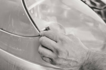 Automobile industry. Close up on car detail - male hand polish in auto repair shop background. Professional person during mechanical maintenance, industrial part transport renovationの写真素材