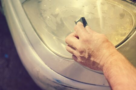 Automobile industry. Close up on car detail - male hand polish in auto repair shop background. Professional person during mechanical maintenance, industrial part transport renovationの写真素材