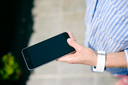 Close up on unrecognizable person holding using mobile phone, abstract modern communication technology background. Busy lifestyle, play game, social network, market strategy, shopping onlineの写真素材