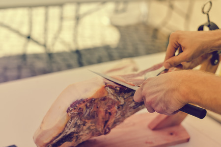 Dry cured ham thinly sliced. Closeup on chef hands in gloves slices prosciutto Italian delicatessen. Festive time backgroundの写真素材