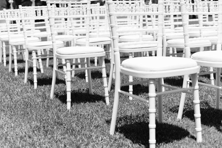 Beautiful arrangement for wedding ceremony event on the natural outdoors lawn park background. Flowers, tables, chairs, elegant romantic decoration details and luxury gathering lifestyleの写真素材