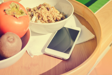 Close up on mobile phone and healthy breakfast modern lifestyle background. Top view mock up flat layの写真素材
