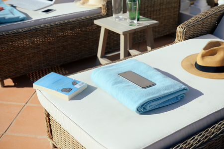 Using mobile smartphone on sunny holiday by swimming pool outdoors background. Relaxing stay in connection, social network mockup display. Close up view photo of leisure luxury lifestyle.の写真素材