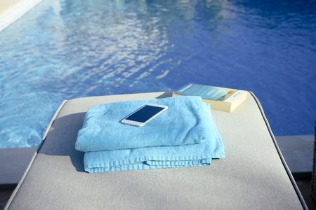 Using mobile smartphone on sunny holiday by swimming pool outdoors background. Close up view photo of leisure luxury lifestyleの写真素材