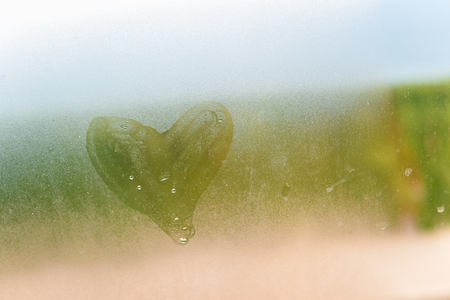 Love heart symbol on a wet misted blurred glass textured background. Creative emotional happiness romance valentines feeling abstractionの写真素材