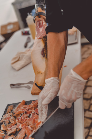 Prosciutto or jamon serrano. Close up on hands of a chef cutting traditional Italian Spanish ham. Slicing prepared hamon gastronomy backgroundの写真素材