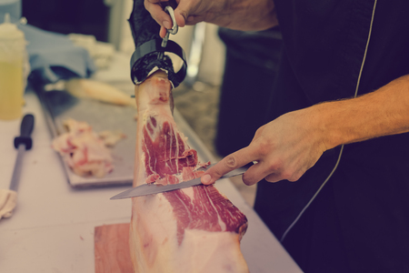 Prosciutto or jamon serrano. Close up on hands of a chef cutting traditional Italian Spanish ham. Slicing prepared hamon gastronomy backgroundの写真素材