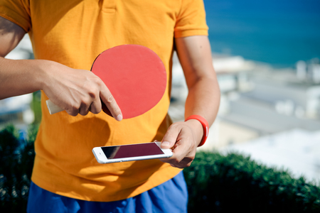 Closeup on hand holding using smartphone and table tennis setの写真素材