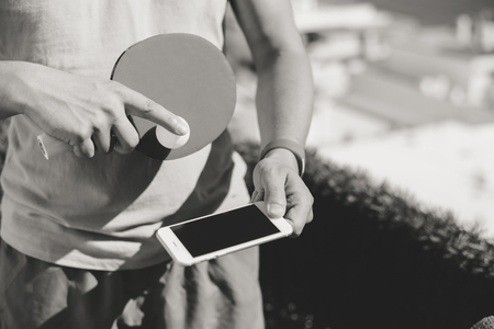 Black and white closeup on hand holding using smartphone and ping pong setの写真素材