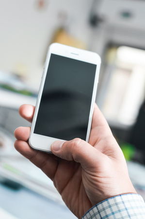 Businessman use mobile phone on light background for photo or video. Writing text, checking calls, reading messages. Close up picture of communication display technology deviceの写真素材