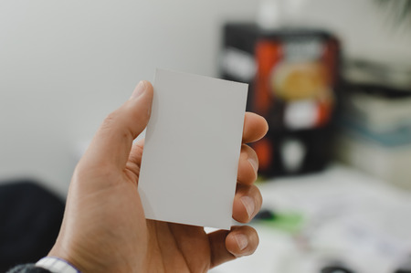 Close up on hand of a businessman showing business card office space backgroundの写真素材
