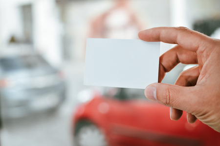 Close up on hand of a businessman showing business card office space backgroundの写真素材
